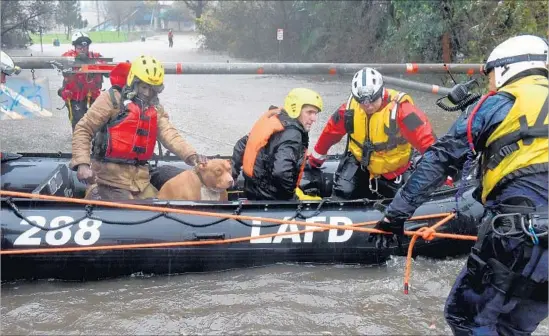  ?? Photograph­s by Michael Owen Baker For The Times ?? HENRY LOFTON, left, with his dog, Brooklyn, and James Chandler are rescued by L.A. Fire Department personnel from the rain-swollen Sepulveda Basin. Several homeless people were rescued along the L.A. River, while in the Inland Empire and Santa Clarita...