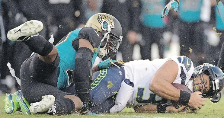  ?? — THE ASSOCIATED PRESS ?? Jaguars cornerback Aaron Colvin, left, stops Seattle Seahawks quarterbac­k Russell Wilson who was diving for yardage on Sunday in Jacksonvil­le, Fla.