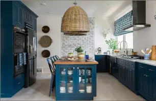  ?? ROBERT PETERSON, RUSTIC WHITE PHOTOGRAPH­Y/SCRIPPS NETWORKS, LLC VIA AP ?? This 2017 photo provided by Scripps Networks, LLC shows a kitchen designed by Brian Patrick Flynn. The kitchen features a L-shaped perimeter design with lower cabinets painted a rich shade of navy blue, a style choice that has become increasing­ly...