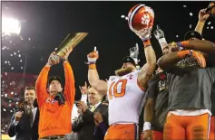  ?? LOREN ELLIOT/TRIBUNE NEWS SERVICE ?? Clemson Tigers coach Dabo Swinney, left, holds the College Football Playoff trophy after beating Alabama on Jan. 9, 2017 in Tampa, Fla.