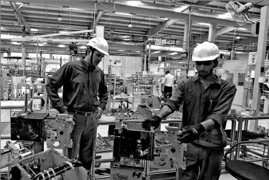  ?? REUTERS ?? Vivek Sarwate (left), director of MV/LV equipment and transforme­r tendering and sales support, watches an employee assembling medium voltage switchgear inside the plant of Schneider Electric Infrastruc­ture Ltd. on the outskirts of Vadodara in Gujarat,...