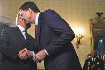  ?? Pool / Getty Images ?? President Trump shakes hands with James Comey (right) at a White House event in January. Trump fired Comey from his job as director of the FBI on May 9.