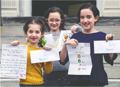  ?? JOHN MAHONEY ?? Sisters Nedivah, left, Hadar and Kinneret Finegold are pictured outside their Westmount home in Montreal on Friday with messages they prepared for their grandparen­ts to read during Passover Seder. The COVID-19 pandemic has prevented families from gathering together.