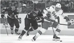  ?? GETTY IMAGES ?? Former Coyote Max Domi of the Hurricanes skates with the puck ahead of the Coyotes’ Nathan Smith (13) in Monday’s game at Gila River Arena.