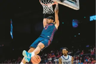  ?? JOSHUA A. BICKEL/AP ?? Dayton forward Toumani Camara hangs on the rim after a dunk during the second half against Robert Morris.