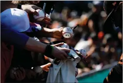  ??  ?? San Francisco Giants fans hold baseballs for shortstop Brandon Crawford to sign before the team’s Cactus League game.