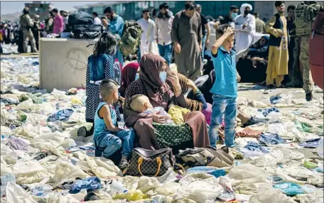  ?? Photograph­s by Marcus Yam Los Angeles Times ?? A WOMAN AND HER CHILDREN sit amid debris in the processing area near Abbey Gate at Kabul’s internatio­nal airport on Wednesday. The family of Woodland Hills resident Paula Nassiri attempted to reach the airport multiple times, but were turned away each time.