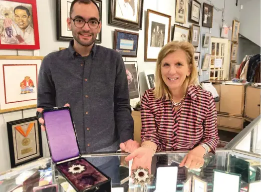  ?? MATTHEW BARAKAT/AP ?? Zachary Diaz and Elizabeth Haynie Wainstein of The Potomack Company display items from the estate of Gen. Colin Powell on Thursday in Alexandria, Va. A collection from the estate of the general of nearly 400 items stretching from the momentous to mundane is currently up for auction.