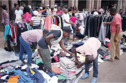  ?? Reuters ?? Shoppers browse used clothings and bags at a market in Harare on Saturday.