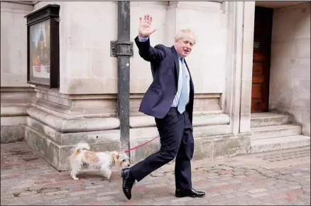  ?? (AP) ?? Britain’s Prime Minister Boris Johnson waves at the media as he leaves with his dog Dilyn after voting at a polling station in London, for local council elections.