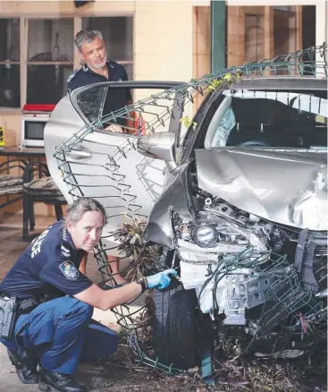  ?? Picture: ANNA ROGERS ?? WRITE-OFF: Forensic Crash Unit Senior Constable Leisa Vagg and Acting Sergeant Lee Chamberlai­n inspect a new Lexus which crashed into a traffic island and power pole in Earlville.