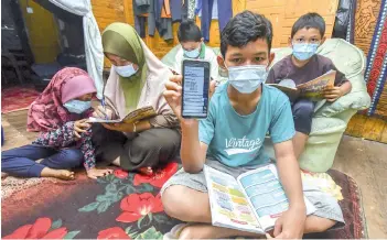  ?? – Bernama photo ?? Mohd Najmuddin Sidek showing the smartphone used by their five siblings to review the online learning when met by reporters at their home at Kampung Sri Kulim Melor in Kelantan yesterday.