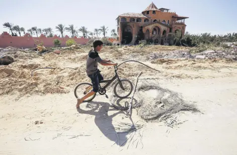  ?? ?? A Palestinia­n boy rides a bike in front of a building damaged in an Israeli attack on Deir al-Balah, Gaza Strip, Palestine, March 23, 2024.