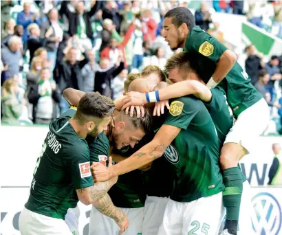  ?? AFP ?? Wolfsburg’s players celebrate a goal against FC Schalke during the Bundesliga match. —