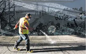  ?? Paul Chinn / The Chronicle ?? Steve Mahoney sprays disinfecta­nt before power washing Jack Kerouac Alley in North Beach for the Public Works department.