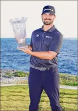  ?? Mike Ehrmann / Getty Images ?? Chad Ramey celebrates with the trophy after winning the Corales Puntacana Championsh­ip on Sunday in Punta Cana, Dominican Republic.