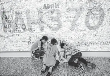  ?? AHMAD YUSNI, EUROPEAN PRESSPHOTO AGENCY ?? Children write a message Monday at the Wall of Hope at Kuala Lumpur Airport in Malaysia.