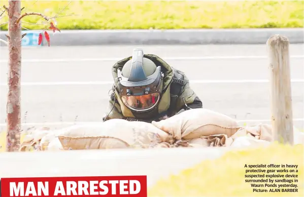  ?? Picture: ALAN BARBER ?? A specialist officer in heavy protective gear works on a suspected explosive device surrounded by sandbags in Waurn Ponds yesterday.