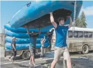  ??  ?? Liquid Descent Rafting employees Angus Harley, foreground, and Kenneth Freeman put away rafts in Kremmling after a group returned from a ride on the scenic Colorado River.