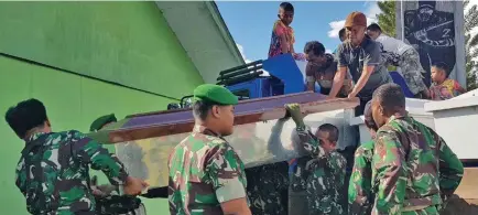  ??  ?? Soldiers prepare coffins for the constructi­on workers in Wamena.