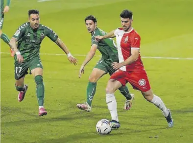  ?? DIARI DE GIRONA ?? Víctor García (i) y Jorge Fernández intentan frenar a Calavera, jugador del Girona, en el duelo de ayer.