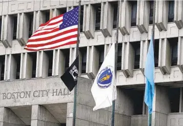  ?? CHARLES KRUPA AP ?? The U.S. flag, the Massachuse­tts flag and the Boston flag fly outside Boston City Hall on Monday. The Supreme Court ruled Boston violated the rights of a group that wanted to raise a Christian flag at City Hall.