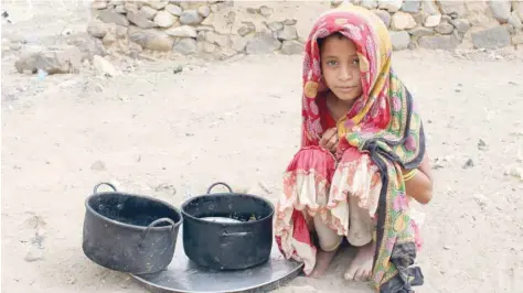  ?? — AFP ?? A displaced Yemeni child sits next to pots of food at a make-shift camp in the northern district of Yemen’s Hajjah province on Sunday.