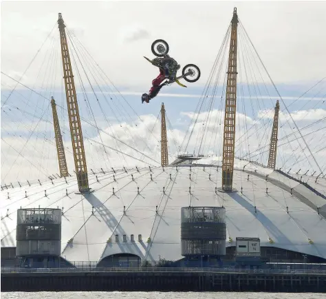  ?? DAREDEVIL: — Reuters ?? Action sports performer Travis Pastrana somersault­s on his motorbike as he jumps between two barges on the River Thames with the O2 Arena sports venue seen behind in London on Thursday.