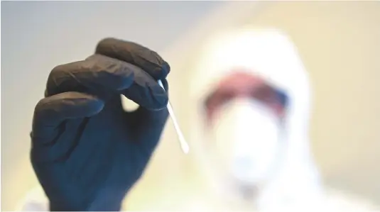  ?? — AFP ?? An employee of an aid organisati­on shows a sample at a newly establishe­d Corona testing station in Dortmund, western Germany.