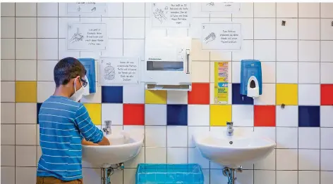  ?? FOTO: OLIVER DIETZE ?? Ein Grundschül­er steht in Furpach summend am Waschbecke­n, um sich die Hände gründlich zu waschen. An der Wand hängen die Corona-Regeln.