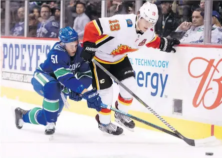  ?? JONATHAN HAYWARD/THE CANADIAN PRESS ?? Vancouver Canucks defenceman Troy Stecher battles for control of the puck with Flames winger Matthew Tkachuk during Wednesday’s season opener at Rogers Arena in Vancouver. The teams meet again Saturday at the Scotiabank Saddledome.