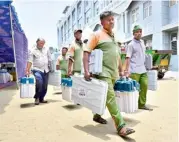  ?? K. MURALI KUMAR ?? Pourakarmi­kas carrying EVMs and VVPAT for distributi­on to o icials on election duty in Bengaluru on Thursday.