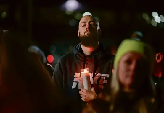  ?? CRAIG F. WALKER/GLOBE STAFF ?? A man listened to music during Thursday night’s vigil in honor of the victims of the Lewiston shootings, in Auburn, Maine.