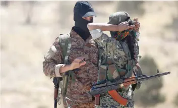  ?? — AFP ?? Members of the Syrian Democratic Forces gather at the entrance of the Syrian town of Tabqa, on Friday as they advance in their battle for the IS stronghold in nearby Raqa.