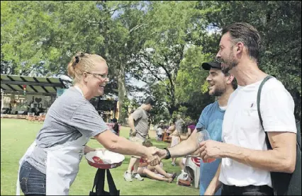  ?? CONTRIBUTE­D BY JENNIFER CARTER ?? Tina Rhoades, baker of the shrimp and grits pie, shakes hands with Daniel Porubiansk­i of Century House Tavern, Woodstock, and is congratula­ted by Brian Jones, chef de cuisine, Kennesaw State University.