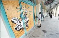  ?? GERALD HERBERT/AP ?? Workers board up windows and doors of shops Sunday in the New Orleans French Quarter ahead of impending storms Marco and Laura.