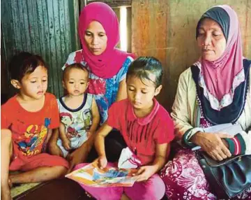  ??  ?? NADIN Junianti (tiga dari kiri) melihat gambar suaminya bersama tiga anak dan ibu mentuanya, Zuana Laudiato, 54, ketika ditemui di rumah mereka di penempatan setinggan berhampira­n Sim-Sim, di Sandakan.