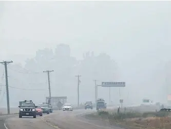  ?? DARRYL DYCK/THE CANADIAN PRESS ?? Smoke from wildfires blankets the area as motorists travel on the Yellowhead Highway in Little Fort, B.C., on Saturday. On Sunday, the B.C. government announced that $100 million would be available to communitie­s and residents affected by wildfires.