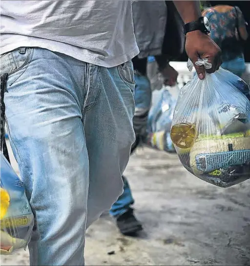  ?? RONALDO SCHEMIDT / AFP ?? Día a día. Gente con bolsas de comida en Caracas el pasado mes de enero.