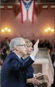  ?? JOSHUA A. BICKEL — THE COLUMBUS DISPATCH VIA AP ?? Ohio Gov. Mike DeWine recites the oath of office as his wife, Fran, holds a pair of family Bibles during his ceremonial swearing-in Monday, Jan. 14, at the Ohio Statehouse in Columbus.