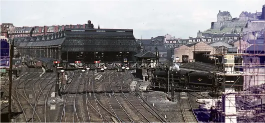  ?? D Sutcliffe/Colour-Rail.com/128027 ?? Viewed from Morrison Street overbridge at the south-west end of the Princes Street/Lothian Road station site, this 13 April 1963 view shows, from left to right, carriage sidings, the Princes Street trainshed with the Caledonian Hotel looming higher as a backdrop, the signal box and turntable, complete with Carstairs-based ‘Black Five’ No 44793 mid-turn, and the Lothian Road goods depot with the high ground of Edinburgh castle as a backdrop. It is worth noting that the Edinburgh & Glasgow Railway main line is in the twin Haymarket tunnels beneath the station, passing directly under the near left-hand corner of the trainshed at a skew angle, and then under Lothian Road, Castle Terrace and King’s Stables Road to emerge in daylight and pass through Princes Street gardens.