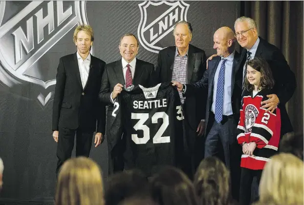  ?? STEPHEN B. MORTON/THE ASSOCIATED PRESS ?? NHL commission­er Gary Bettman, second from left, displays a jersey after announcing that Seattle had been awarded the league’s 32nd franchise on Tuesday. Joining Bettman at the ceremony are team owners Jerry Bruckheime­r, left, David Bonderman and David Wright, team president Tod Leiweke, and Washington Wild youth hockey player Jaina Goscinski.