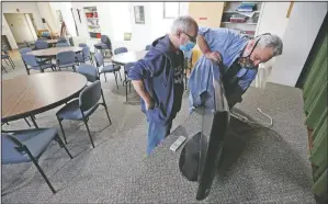  ?? (Telegraph Herald/Nicki Kohl) ?? Mykaela Delaney (left) and Brian Baker set up a television for use by residents of the Almost Home guest house in a community room at St. John’s Lutheran Church in Dubuque, Iowa.