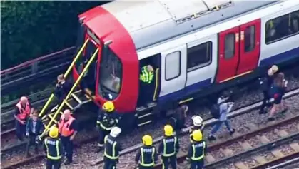  ??  ?? Evacuation: Schoolchil­dren are escorted from the Tube carriage by emergency services