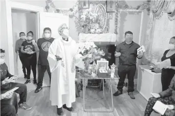  ?? JOHN MINCHILLO/AP 2020 ?? The Rev. Fabian Arias performs an in-home service last May beside the remains of Raul Luis Lopez in the Corona neighborho­od of the Queens borough of New York. Lopez died last April from COVID-19.
