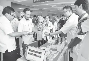  ??  ?? Abu Hassan (left) takes a closer look at the display in the diabetes booth.