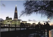  ?? — Reuters ?? People walk alongside the Thames as the sun sets behind The Shard in London, Britain.