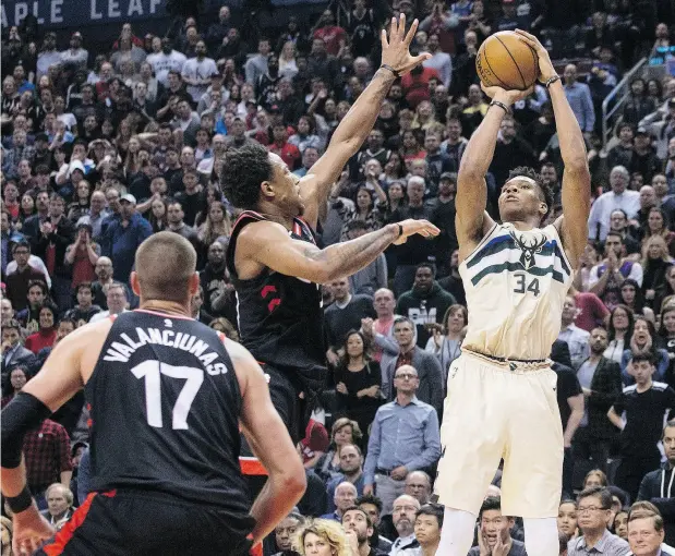  ?? CHRIS YOUNG / THE CANADIAN PRESS ?? Milwaukee Bucks’ Giannis Antetokoun­mpo scores on Raptors’ DeMar DeRozan, centre, as Jonas Valanciuna­s looks on Friday in Toronto.