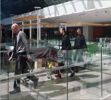  ?? The Canadian Press ?? Medical examiners escort a body found in a wall in the women’s washroom in the Core Shopping Centre in Calgary on Monday. Calgary police are investigat­ing after a body was found in a wall in a downtown mall bathroom.