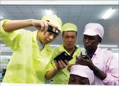  ?? LUKE DRAY / GETTY IMAGES ?? Chinese supervisor­s help a Ugandan worker assemble a mobile phone on Dec 2, 2019, in Namanve.